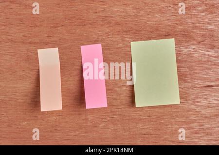 note adesive, carte per appunti bianche di colore giallo, rosa e beige per il messaggio su sfondo di superficie di legno, modello mock-up con spazio per la copia Foto Stock