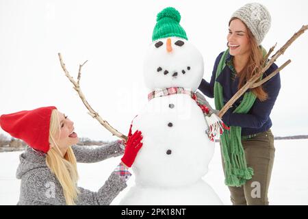 Lo spirito dell'inverno. due amici che costruiscono un pupazzo di neve insieme. Foto Stock
