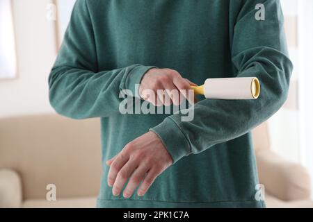 Uomo che pulisce la felpa verde con il rullo di lanugine all'interno, primo piano Foto Stock