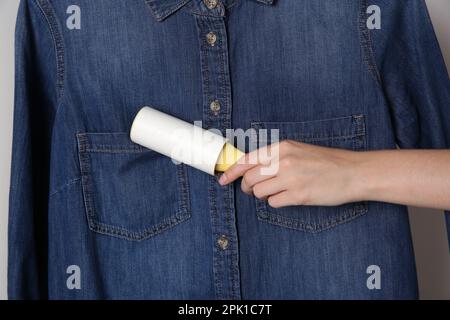 Donna pulizia camicia in denim con rullo per pelucchi, primo piano Foto Stock