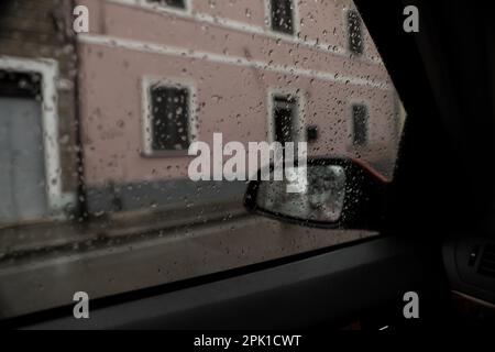 Tempo piovoso in città, vista attraverso il finestrino coperto di gocce Foto Stock