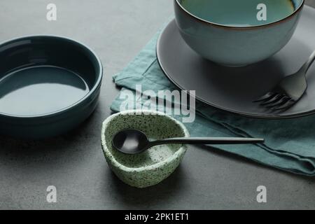 Set di eleganti stoviglie e posate vuote sul tavolo grigio Foto Stock