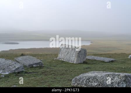 Novakovići, Žabljak, Montenegro – Agosto 2022: Stećak sul cimitero medievale „Grčko groblje“ e Riblje jezero (lago). Cimitero è iscritto sul Worl Foto Stock