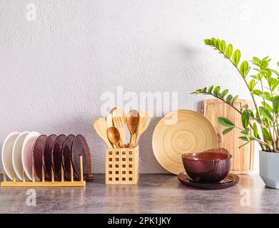piatti ecologici e utensili da cucina sullo sfondo di un muro di cemento grigio su un piano di pietra. utensili di legno. Elementi ECO Foto Stock