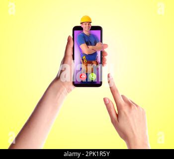 Donna con smartphone che chiama un riparatore professionista su sfondo giallo, primo piano Foto Stock