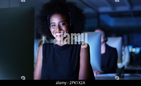 Sono riuscito e felice. Ritratto corto di una giovane donna d'affari attraente che indossa una cuffia e che siede in ufficio a tarda notte. Foto Stock