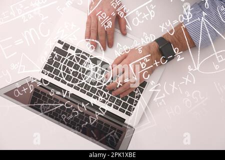 Concetto di scienza e istruzione. Illustrazione delle formule di fisica e matematica di base e dell'uomo che lavora sul laptop al tavolo, vista dall'alto Foto Stock