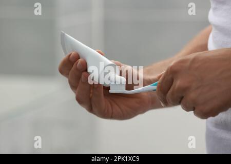 Uomo che applica dentifricio su pennello in bagno, primo piano Foto Stock