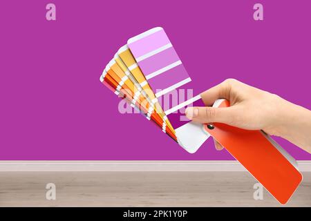 Decoratore che tiene campioni di tavolozza di colori in camera con parete dipinta, primo piano. Ristrutturazione degli interni Foto Stock
