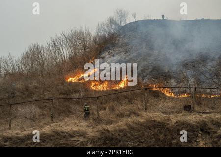 VLADIVOSTOK, RUSSIA - 4 APRILE 2023: I vigili del fuoco hanno messo fuori erba secca bruciante. Disastro naturale. Foto Stock