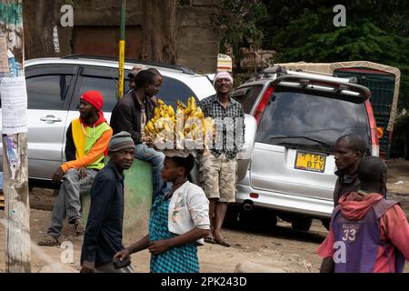 Arusha, Tanzania - 17th ottobre 2022: Una strada trafficata con una donna che porta le banane sulla testa. Foto Stock