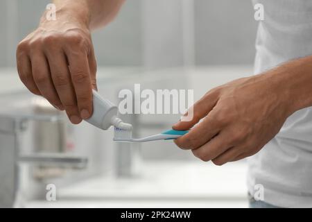 Uomo che applica dentifricio su pennello in bagno, primo piano Foto Stock