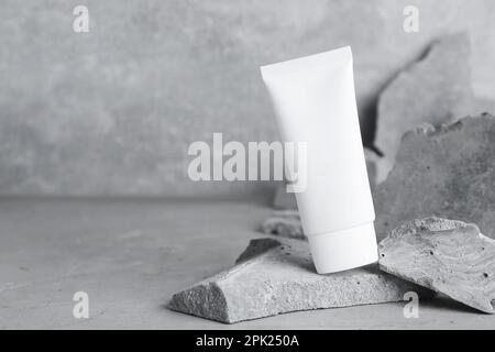 Tubo di crema per le mani tra le pietre su sfondo grigio. Modello per il design Foto Stock