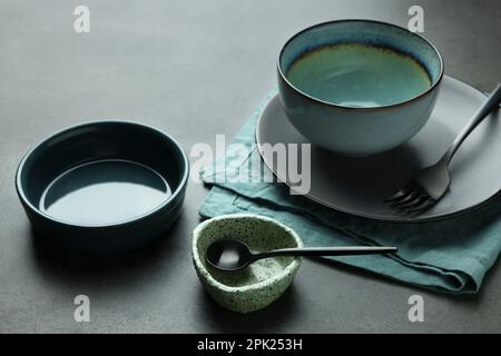 Set di eleganti stoviglie e posate vuote sul tavolo grigio Foto Stock