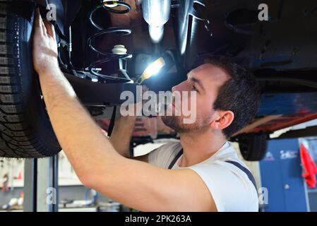 Professional meccanico lavora in un laboratorio e riparazioni veicoli - controllare la tecnologia, freni e pneumatici Foto Stock