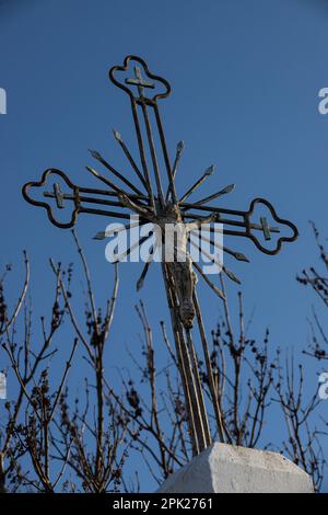 Vecchia croce di metallo con un crocifisso su uno sfondo cielo senza nuvole. Immagine verticale. Foto Stock