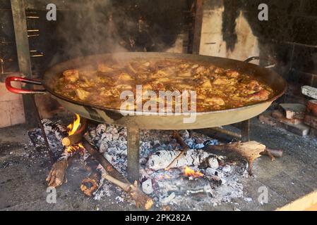 cucinare una paella tradizionale sopra il fuoco di legna Foto Stock