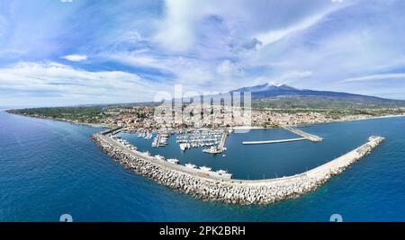 Destinazione estiva Riposto - veduta aerea dall'alto sul porto con barche durante le giornate di sole con vulcano Etna sullo sfondo del mare Foto Stock