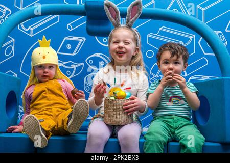 City Art Centre, Edimburgo, Scozia, Regno Unito, 05 aprile 2023. Edinburgh Science Festival: I bambini si preparano per Pasqua rotolando le colorate uova di Pasqua giù per uno scivolo costruito da blocchi di costruzione dall'installazione Imagination Playground. Il City Art Centre dispone di cinque piani di laboratori scientifici pratici e attività ed è il principale luogo di ritrovo per famiglie del Festival, che offre divertimento educativo per tutta la giornata per i bambini tra i 3 e i 12 anni. Nella foto: Giacomo di 18 mesi, Dorothy (4 anni) e Kofi (18 mesi) godono di uova di Pasqua al cioccolato. Credit: Sally Anderson/Alamy Live News Foto Stock