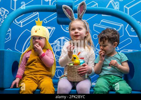 City Art Centre, Edimburgo, Scozia, Regno Unito, 05 aprile 2023. Edinburgh Science Festival: I bambini si preparano per Pasqua rotolando le colorate uova di Pasqua giù per uno scivolo costruito da blocchi di costruzione dall'installazione Imagination Playground. Il City Art Centre dispone di cinque piani di laboratori scientifici pratici e attività ed è il principale luogo di ritrovo per famiglie del Festival, che offre divertimento educativo per tutta la giornata per i bambini tra i 3 e i 12 anni. Nella foto: Giacomo di 18 mesi, Dorothy (4 anni) e Kofi (18 mesi) godono di uova di Pasqua al cioccolato. Credit: Sally Anderson/Alamy Live News Foto Stock