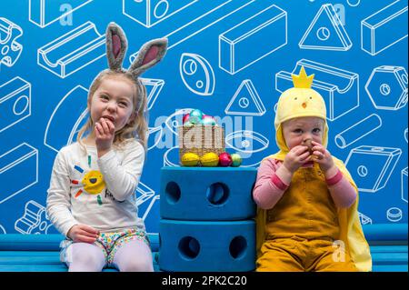 City Art Centre, Edimburgo, Scozia, Regno Unito, 05 aprile 2023. Edinburgh Science Festival: I bambini si preparano per Pasqua rotolando le colorate uova di Pasqua giù per uno scivolo costruito da blocchi di costruzione dall'installazione Imagination Playground. Il City Art Centre dispone di cinque piani di laboratori scientifici pratici e attività ed è il principale luogo di ritrovo per famiglie del Festival, che offre divertimento educativo per tutta la giornata per i bambini tra i 3 e i 12 anni. Nella foto: Dorothy, di 4 anni e James, di 18 mesi, godono di uova di Pasqua al cioccolato. Credit: Sally Anderson/Alamy Live News Foto Stock