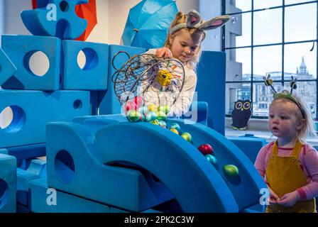 City Art Centre, Edimburgo, Scozia, Regno Unito, 05 aprile 2023. Edinburgh Science Festival: I bambini si preparano per Pasqua rotolando le colorate uova di Pasqua giù per uno scivolo costruito da blocchi di costruzione dall'installazione Imagination Playground. Il City Art Centre dispone di cinque piani di laboratori scientifici pratici e attività ed è il principale luogo di ritrovo per famiglie del Festival, che offre divertimento educativo per tutta la giornata per i bambini tra i 3 e i 12 anni. Nella foto: Dorothy, 4 anni di esperienza con le uova di Pasqua e uno scivolo guardato da James, 18 mesi. Credit: Sally Anderson/Alamy Live News Foto Stock