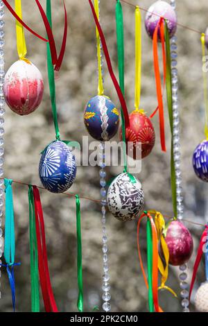 Le uova dipinte pendono dai rami dell'albero di Pasqua. Il fuoco è su un uovo giallo dipinto dai bambini a mano. Foto di alta qualità Foto Stock