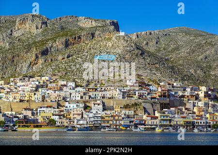 Cappella bianca e bandiera greca dipinta sulla collina sopra Pothia, la città principale di Kalymnos, isola greca, Isole Dodecanesi, Grecia Foto Stock