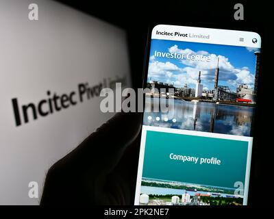 Persona in possesso di cellulare con pagina web della società australiana Incitec pivot Ltd. Sullo schermo di fronte al logo. Messa a fuoco al centro del display del telefono. Foto Stock