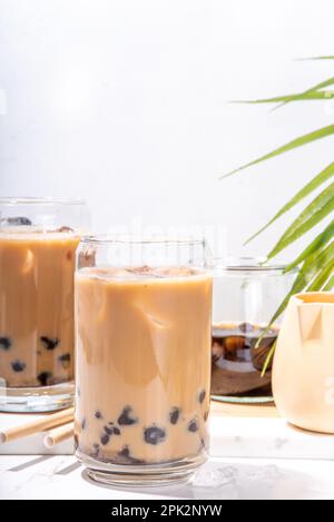 Caffè tapioca ghiacciato latte o bolle di boba perla tè al latte, caffè freddo alla moda asiatica bevanda con palline di tapioca e ghiaccio tritato, su sfondo di marmo bianco Foto Stock