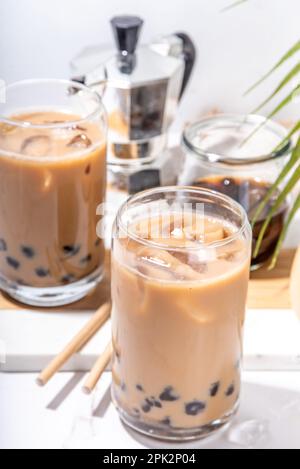 Caffè tapioca ghiacciato latte o bolle di boba perla tè al latte, caffè freddo alla moda asiatica bevanda con palline di tapioca e ghiaccio tritato, su sfondo di marmo bianco Foto Stock