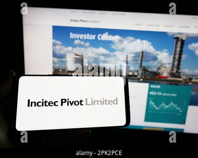 Persona che tiene il telefono cellulare con il logo della società australiana Incitec pivot Ltd. Sullo schermo di fronte alla pagina web aziendale. Messa a fuoco sul display del telefono. Foto Stock