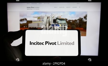 Persona che tiene il cellulare con il logo della società australiana Incitec pivot Ltd. Sullo schermo di fronte al sito web aziendale. Messa a fuoco sul display del telefono. Foto Stock