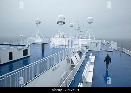 Un uomo con il tempo piovoso e nebbioso sul ponte del traghetto Norroena con l'elettronica marina e il Nord Atlantico Foto Stock