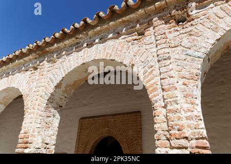 Un maestoso edificio in mattoni con splendidi archi e finestre illuminate si erge alto contro un cielo blu Foto Stock