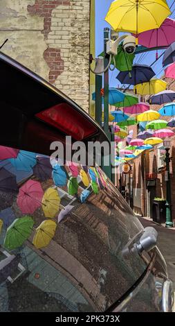 Redlands, California - 27 aprile 2019: Ombrelli colorati appesi sopra Orange Street Alley nel centro di Redlands. Un riflesso in un finestrino posteriore dell'auto. Foto Stock