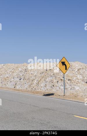 Curva davanti segno di attenzione su una strada solitaria desolata nel deserto di Mojave di Amboy, California Foto Stock