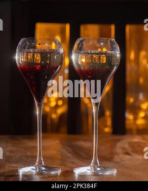 Bere il Kir Royal, cocktail francese di aperitivo a base di crema di cassis con champagne, tipicamente servito in bicchieri di tulipano serviti al bar Foto Stock