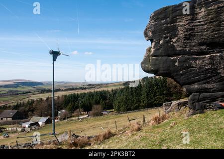 Intorno al Regno Unito - Un mulino a vento domestico regolato contro gli affioramenti della pietra gritstone su Bridestones Moor, Todmorden Foto Stock