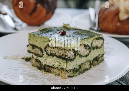 Primo piano e dettagli di una torta Matcha giapponese a strati su un piatto bianco con sfondo sfocato Foto Stock