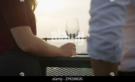 Donna in possesso di vino rosso bere vino con il tramonto sulla vista della città alto edificio Foto Stock