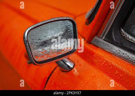 Specchietto retrovisore di un'auto retrò arancione nel closeup pioggia Foto Stock