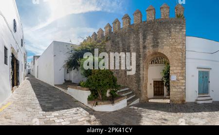 Vejer de la Frontera, Cadice, Spagna - 02 aprile 2023: Vista panoramica di una strada a Vejer de la Frontera e una delle porte del vecchio castello della cittadella Foto Stock