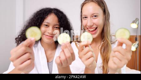 Diverse donne di amici vicini che fanno un trattamento di bellezza insieme tenendo cetriolo Foto Stock