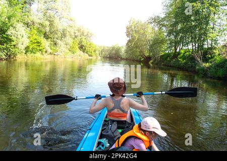 Gita in kayak in famiglia. Mamma e figlia canottano una barca sul fiume, un'escursione in acqua, un'avventura estiva. Eco-friendly e turismo estremo, attivo e sano Foto Stock