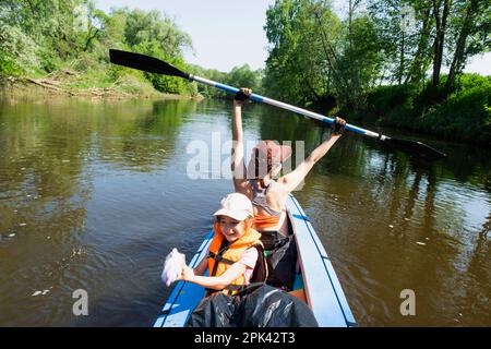 Gita in kayak in famiglia. Mamma e figlia canottano una barca sul fiume, un'escursione in acqua, un'avventura estiva. Eco-friendly e turismo estremo, attivo e sano Foto Stock