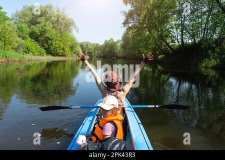 Gita in kayak in famiglia. Mamma e figlia canottano una barca sul fiume, un'escursione in acqua, un'avventura estiva. Eco-friendly e turismo estremo, attivo e sano Foto Stock