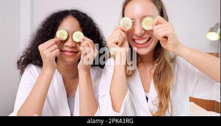 Diverse donne di amici vicini che fanno un trattamento di bellezza insieme tenendo cetriolo Foto Stock