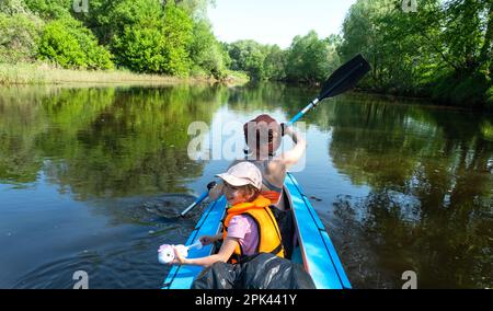 Gita in kayak in famiglia. Mamma e figlia canottano una barca sul fiume, un'escursione in acqua, un'avventura estiva. Eco-friendly e turismo estremo, attivo e sano Foto Stock