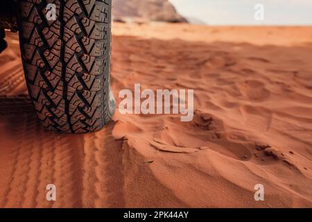 4wd pneumatico del veicolo sporco da polvere - traccia stampata visibile in sabbia rossa, dettaglio primo piano Foto Stock